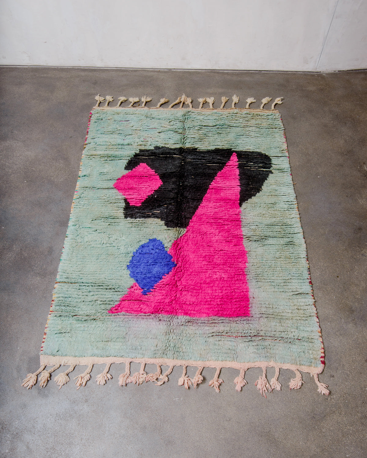 Berberlin vintage boujad rug in colourful wool laying flat on concrete floor.